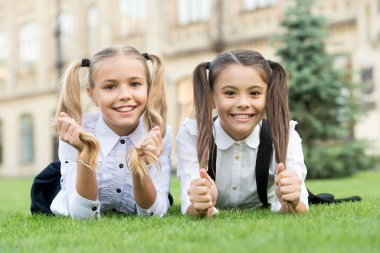 Okul arkadaşları resmi kıyafetler yeşil çimlerde dinlenme, çocuk bakımı konsepti