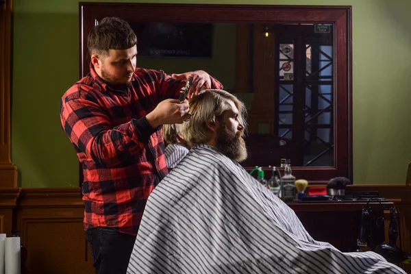 El hombre quiere un peinado nuevo. belleza masculina y la moda. un hombre maduro en la barbería. hombre barbudo brutal en la peluquería. peluquero profesional con cliente masculino. hipster con barba teñida y bigote — Foto de Stock