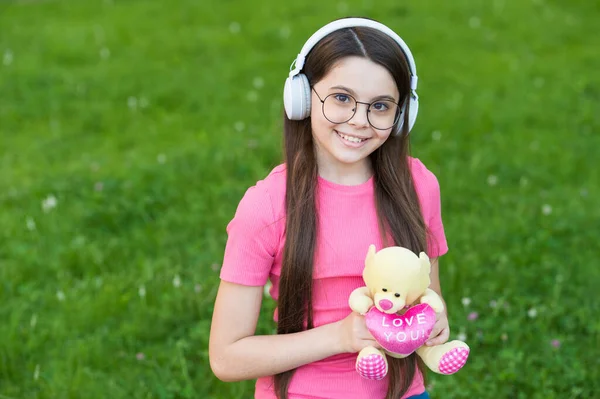 Дівчина слухає літню мелодію бездротові навушники фон природи, концепція щасливого дитинства — стокове фото