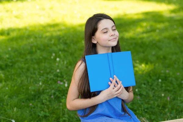 Маленькая счастливая девочка читает книгу на открытом воздухе солнечный день, счастливый конец концепции — стоковое фото