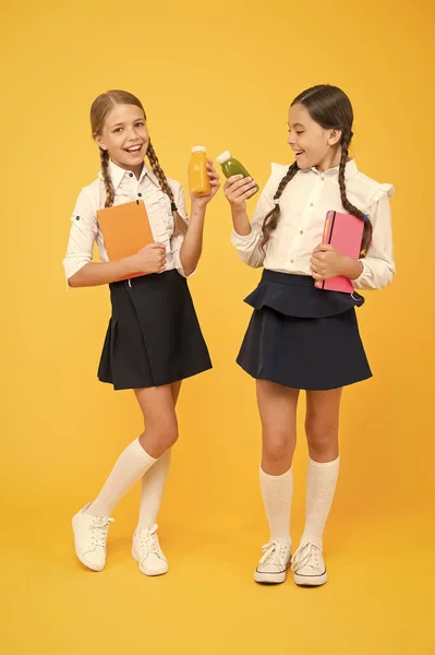 Comida saudável é vida saudável. Os alunos bebem sumo na biblioteca. comida saudável. diário e laticínios. Hora do almoço. meninas pequenas com livro. meninas felizes estudar com bloco de notas. lição de literatura. voltar para a escola — Fotografia de Stock