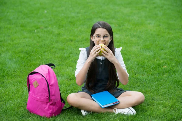 Food for healthy tooth. Little kid eat apple sitting on green grass. School snack. Health education. Dental diet. Dental health. Oral hygiene. Dental care. Preventing cavities. Pediatric dentistry