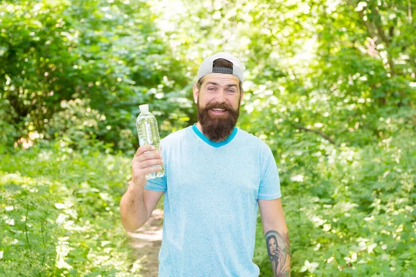 Återfukta. brutal brunett skäggig man dricka vatten. mogen kille med skägg i trä. Varm sommardag. Jag känner mig törstig. En skäggig man ser glad ut. brunett skäggig man med vattenflaska i skogen — Stockfoto