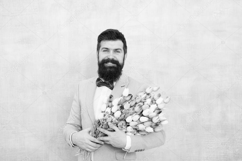 Valentines Day is finally here. Bearded man hold valentines flowers. Happy hipster with tulip bouquet. Valentines day celebration. Florists deliver on Valentines. Womens day. March 8. Spring