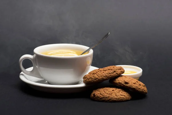 Kekse in der Nähe von Tee auf dunkelgrauem Hintergrund. Süße Bäckerei — Stockfoto