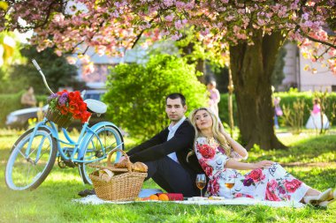 Güzel atmosfer. Çiftler, sakura çiçeklerinin altında battaniyede buluşurlar. Kamp yapmak. Aşık mutlu bir çift. Kadın ve erkek parkta uzanıp günün tadını çıkarıyorlar. Sevgililer günü pikniği. Parkta romantik piknik