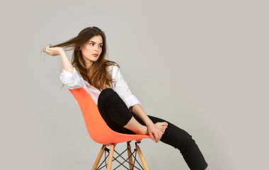 Moda mankeni sıradan görünüyor. Evde kal. Saçını keratin kolajen amino asit ve bitkisel özlerle doyur. Yaz makyajı. Kız sandalyeye oturur. Doğal makyajlı bir kız. Kadın şehvetli görünümü