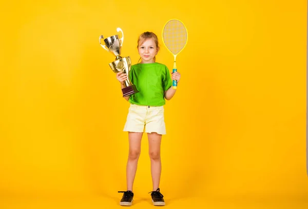 Infanzia felice. piccola ragazza tenere coppa campionato e racchetta da tennis. Campione di badminton. Vittoria e vittoria. Meritato premio. Risultati sportivi. concetto di successo sportivo. felice giorno dei bambini — Foto Stock