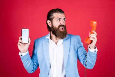 Adam eski telefonları ve akıllı telefonları karşılaştırıyor. Telefonun evrimi. İki farklı telefon teknolojisi. Eski ve yeni. İletişim yöntemleri. Karşılaştırmalı teknoloji kavramı. Karşılaştırma