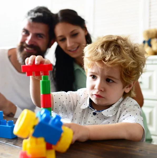 Mom, dad and boy build out of plastic blocks