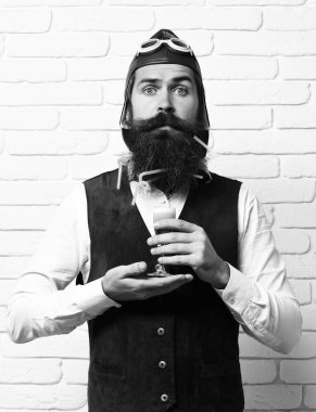 Beyaz tuğlalı arka planda yakışıklı sakallı pilot şaşırdı.