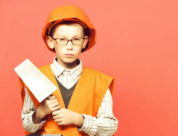 Young cute builder boy on red studio background, copy space — стоковое фото