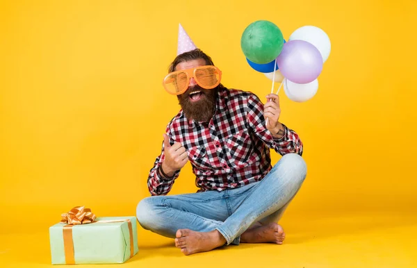 Den Erfolg zu spüren. Ein fröhlicher Mann mit Bollenhut hält Urlaubsballons in der Hand. Geschenke und Geschenke Konzept. Wir wünschen Ihnen einen schönen Urlaub. Partyzeit. Alles Gute zum Geburtstag. bärtiger älterer Mann feiert Geburtstagsparty — Stockfoto