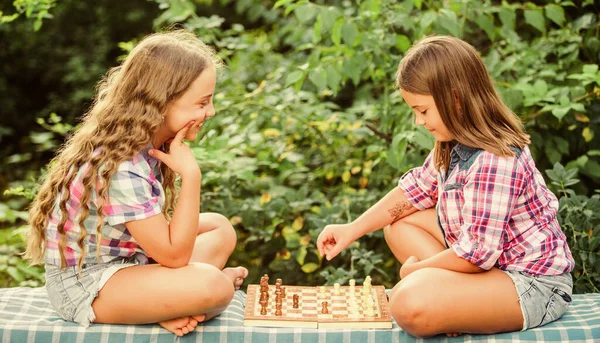 Cognitive development. Intellectual game. Make decision. Smart children. Children play chess outdoors nature background. Sport and hobby concept. Little girls play chess. Sisters playing chess