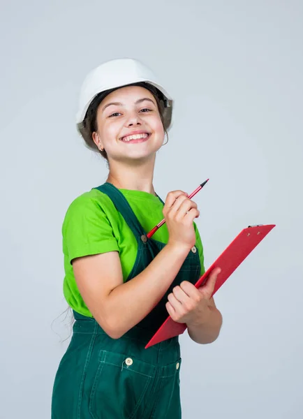 Belo sorriso. Planejamento de reparo. Um miúdo de chapéu duro a fazer anotações. pasta de documento criança hold. O miúdo aprende a ser construtor de trabalhadores da construção civil com chapéu de segurança. Criança no capacete com tablet — Fotografia de Stock