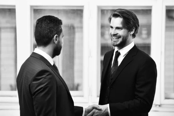 Ділові партнери. Двоє бізнесменів посміхаються і тремтять руками — стокове фото