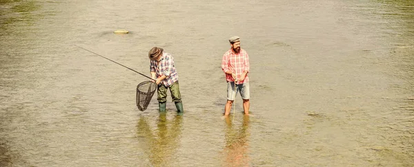 競争だ。釣竿と網を持った2人の幸せな漁師。父と息子の釣り。冒険だ。レクリエーションやレジャーの屋外。大きなゲーム釣り。男性の友情。趣味とスポーツ活動。トラウト・ベイト — ストック写真