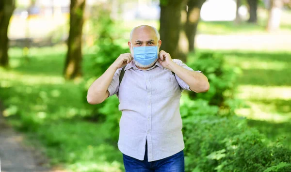 Viselj maszkot a parkban. Törődj az egészségeddel. védd meg magad a vírustól. Védőmaszkos férfi. séta a szabadban a koronavírus karanténban. a világjárvány idején betartják az óvintézkedéseket. egészséges élet — Stock Fotó