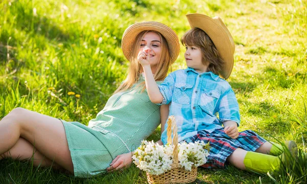 Du temps en famille. mère et enfant se détendent dans le parc. pique-nique sur herbe verte. fleur de printemps dans le panier. mère et fils en chapeau de paille. Joyeux jour de famille. fête des mères. petit garçon aime maman. vacances d'été — Photo