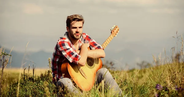 Tiempo agradable a solas. Músico buscando inspiración. Un vagabundo soñador. Humor pacífico. Un tipo con guitarra contempla la naturaleza. Concepto de vagabundeo. Inspirando la naturaleza. Verano vacaciones tierras altas naturaleza — Foto de Stock