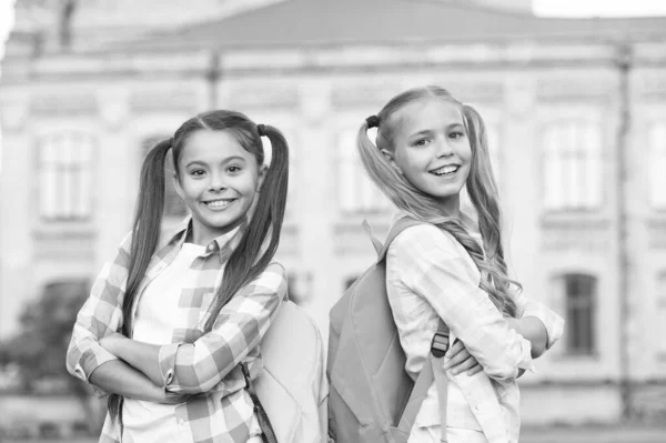 Ferien er over. Tilbake til skolen. Søte skolejenter med lange hestehaler. Slutten på skoleåret. Muntre, smarte skolejenter. Glade skolejenter utendørs. Små skolejenter med ryggsekk. September – stockfoto