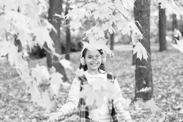 Quand les feuilles tombent. Petite fille jouer avec des feuilles en écoutant de la musique. Joyeux enfant amusez-vous avec des feuilles d'automne. Feuilles changer de couleur en automne — Photo