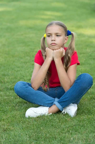 緑の芝生の上でリラックスした女の子かわいいポニーテールの髪型、悲しい日のコンセプト — ストック写真