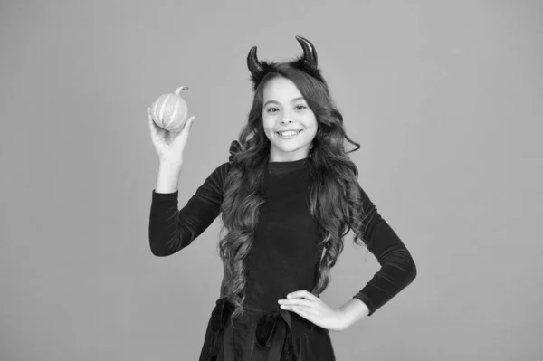 Tallado de calabaza y caza de fantasmas. Niño de fiesta de Halloween. Niño feliz mantenga calabaza fondo naranja. Un niño pequeño usa cuernos rojos del diablo. Halloween mirada de niña pequeña. Celebración festiva —  Fotos de Stock