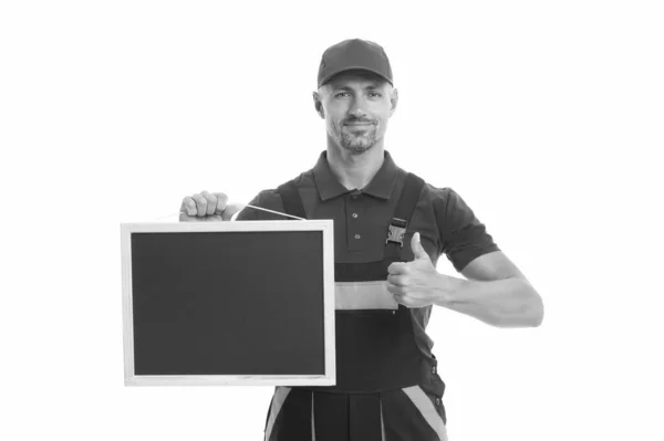 Ele adora o seu trabalho. Trabalhador do sexo masculino em cap hold quadro negro. placa para espaço de cópia. anúncio de serviço construtor. melhor oferta de sempre. mover para fora ou deslocalização carregador. reparador qualificado oferece seus serviços — Fotografia de Stock