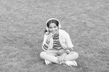 Hallet şu işi. Dışarıda dinlenirken müzik dinlemek. Çocuk yeşil çayır müziğinin tadını çıkarıyor. Keyifli zaman. Çocuk kulaklıkları müzik dinler. Havalı kız kulaklıkları müzik dinliyor. Eğitici podcast