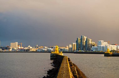 Deniz manzarası ve parlak deniz feneriyle ufuk çizgisi. Deniz limanı navigasyon konsepti. Deniz ulaşımı ve seyrüsefer. Reykjavik İzlanda 'daki rıhtımdaki deniz feneri. Deniz feneri sarı parlak kule deniz kıyısında