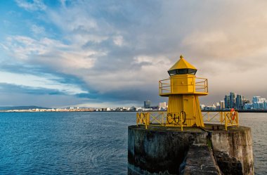 Reykjavik deniz feneri kulesi İzlanda 'daki taş iskelede. Denizdeki deniz feneri. Deniz manzaralı ve siluetli mimari. Navigasyon yardımı ve varış yerleri. Reykjavik, İzlanda 'ya seyahat.