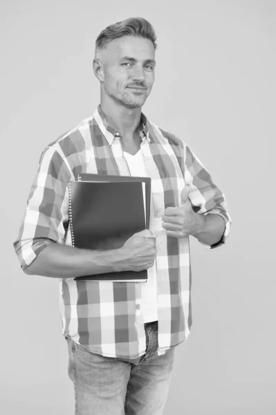 Bela escola ou professor universitário. polegar para cima. adulto homem estudante segurando cadernos. homem com pasta de fundo amarelo. O empresário guarda o livro para anotações. O tipo tem bloco de notas para escrever. Fazendo pesquisa — Fotografia de Stock