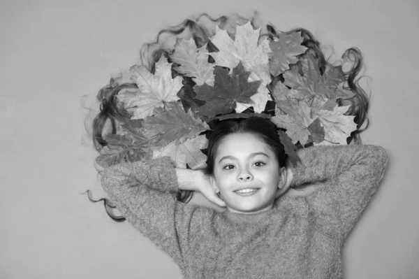 El otoño es razón para sonreír. Otoño look de pequeño modelo de belleza. Chica feliz con hojas de otoño en el pelo largo. Belleza natural. Peluquería. El otoño es la estación cuando cada hoja es una flor — Foto de Stock