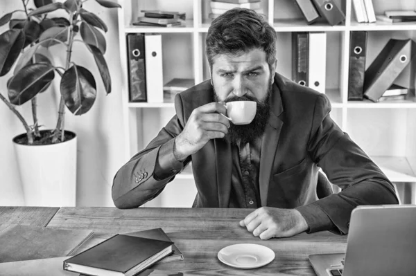 tired man drink coffee. need more energy. early morning drink. modern office life. mature businessman at workplace. exhausted and overworked. ceo sit at table with notebook and laptop