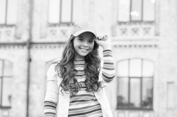 Beleza funky. sorriso caloroso e amigável. conceito de cabelo saudável. menina bonito tem cabelo encaracolado. criança morena bonita na rua. moda de primavera e beleza. feliz dia das crianças. garoto elegante em cap — Fotografia de Stock