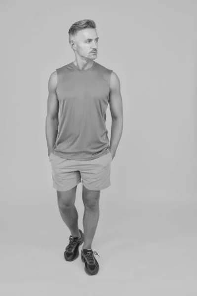 Deportista en camiseta y pantalones cortos sobre fondo violeta. hombre en  ropa casual azul. macho en ropa deportiva para hacer ejercicio o entrenar  en la pared púrpura. estilo y tendencia de moda
