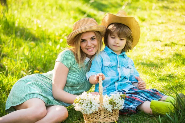 We are family. summer holiday vacation. mother and kid relax in park. picnic on green grass. spring bloom in basket. mother and son in straw hat. happy family day. mothers day. small boy love mom