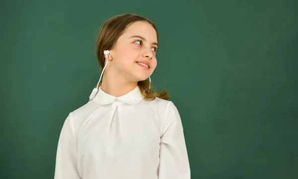 Luisterboek. Studenten meisje in koptelefoon op schoolbord achtergrond kopieerruimte. Audio vertaling. Meisje met koptelefoon die naar muziek luistert. Audioleerconcept. Thuisonderwijs online onderwijs — Stockfoto