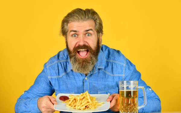 Watch sport match at pub. Man drink beer and eat snacks. Bar restaurant. Cheerful man bearded hipster drinking beer. Enjoy football on tv. Perfect french fries. Consume alcohol. Beer and food