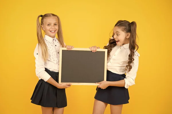 Glad to inform. Schoolgirls informing you. School girls hold blank chalkboard copy space. Girls school uniform hold blackboard. Back to school concept. Upcoming events in school. Visual communication