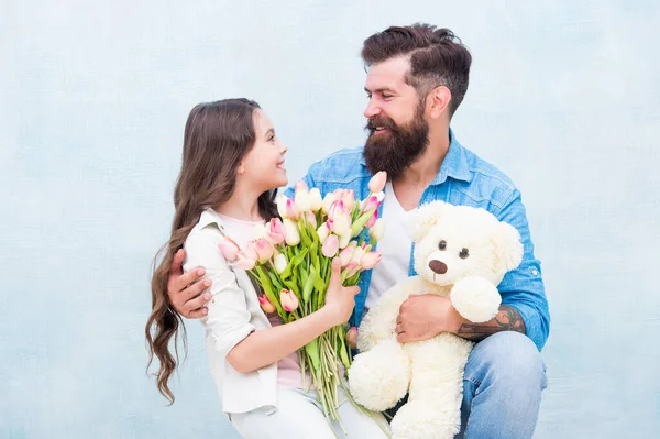 One adoption is enough to change lives. Adoptive family. Bearded man and little girl hold flowers and toy. Child adoption. Adoption and parenthood. Parental relationship. Happy daughter, happy father