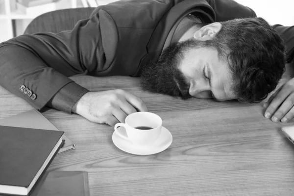 Ez nem segít. A jóképű főnök az irodában alszik, kávét iszik. Kényelmes munkaterület. Kemény reggel. Szakállas hipster formális öltöny lazít a kávéval. Irodai rutinok. Az első kávé. Álmatlan éjszaka — Stock Fotó
