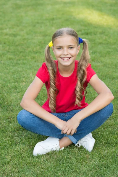 女の子かわいいポニーテールヘアスタイル緑の芝生の上でリラックス,楽観的な概念 — ストック写真