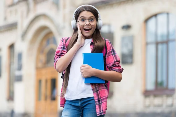 Erstaunliche Audio-Inhalte. Überraschtes Kind hört Hörbuch im Freien. Hörstunde. Neue Technologie. Englische Schule. Fremdsprachen lernen. Modernes Leben. Musikerziehung. Alles, was Sie brauchen, sind Ihre Ohren — Stockfoto