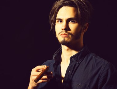 Sigara içen ciddi sakallı bir adam.