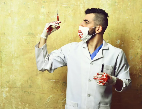 Spritze mit Blut in der Hand des Arztes in Eingriffsmaske — Stockfoto