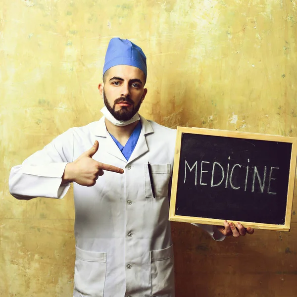 Doctor con barba apuntando a la pizarra con la palabra medicina —  Fotos de Stock