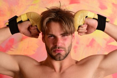 Çıplak gövdeli adam altın boks eldiveni giyiyor.