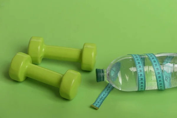 Hantle w jasnozielonym kolorze, butelka wody i taśma pomiarowa — Zdjęcie stockowe